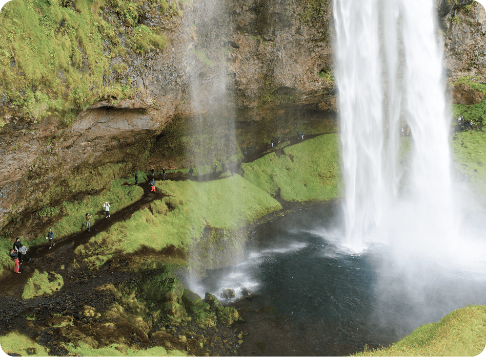 Waterfall cascading over lush green landscape trail.